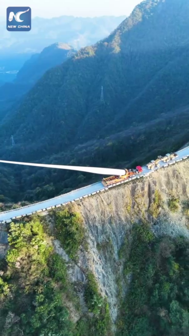 Cina: pala di turbina eolica gigante trasportata su una ripida cresta montuosa